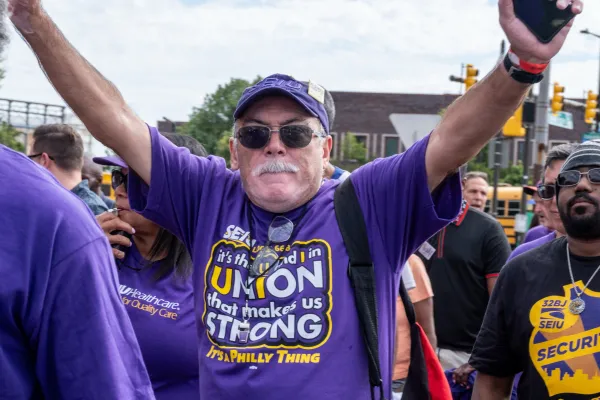 Man wearing SEIU 32 BJ swag with his arms up in the air