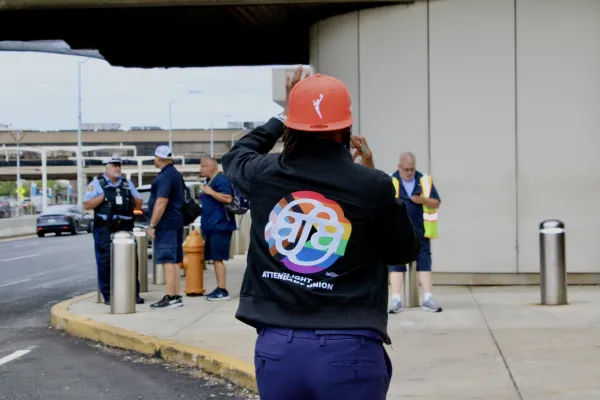 Worker walking away from the camera wearing a black jacket with a rainbow AFA logo on it