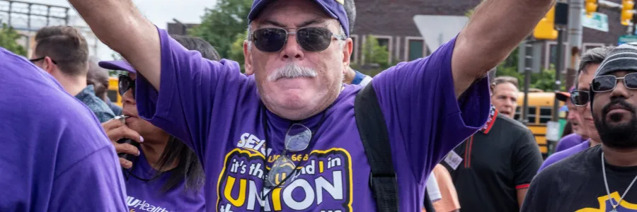 Man wearing SEIU 32 BJ swag with his arms up in the air