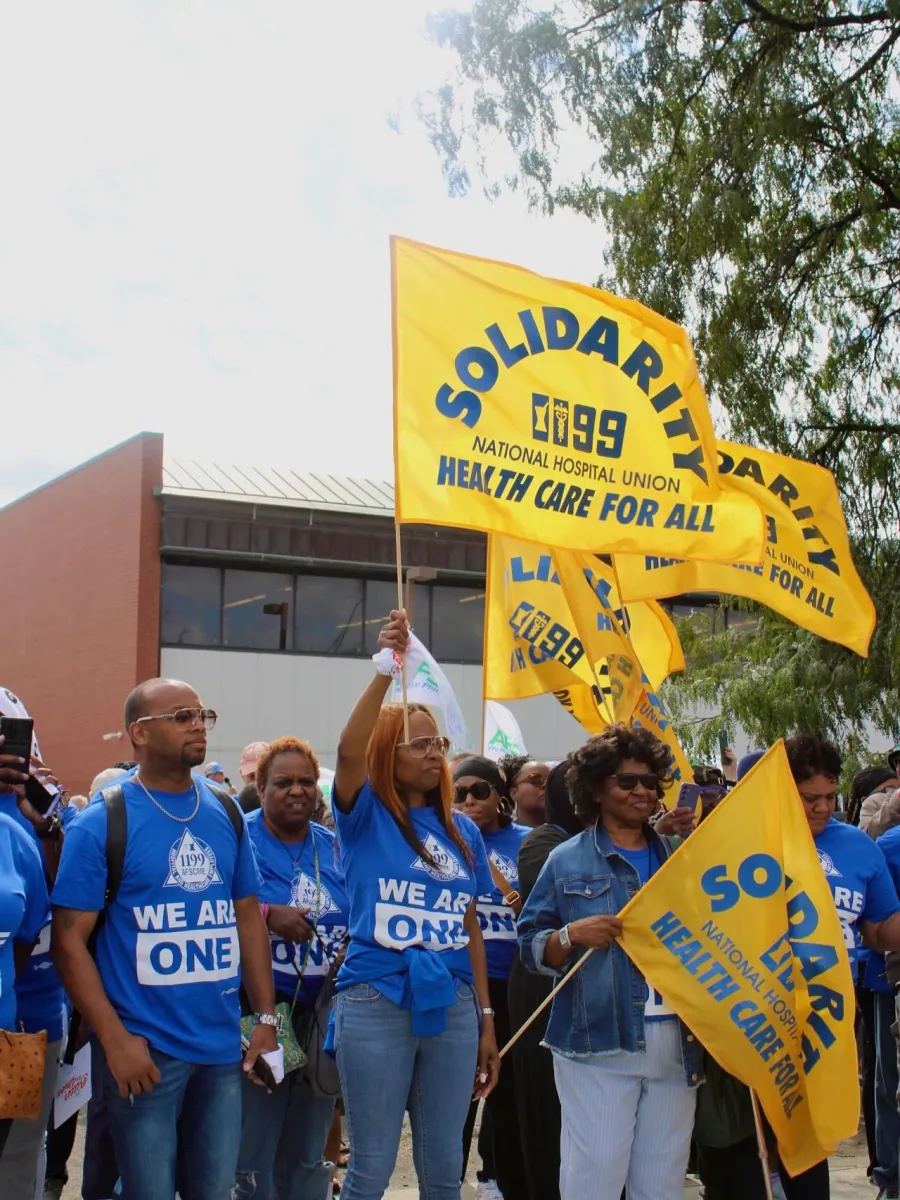Members of 1199C wearing blue shirts and holding gold flags that say Solidarity on them