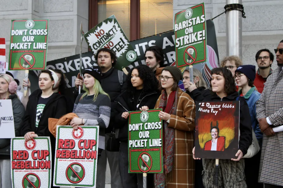 Starbucks Worker United members holding Starbucks branded signs 